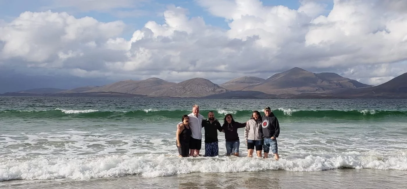 Guides Hugh Allison and Mark Addison in the ocean at Luskentyre beach with happy customers taken on one of Hebrides Tours